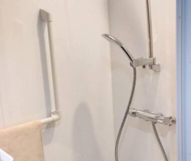 Compact shower stall with handheld head, stool, towel and safety grab bar in Yura Onsen Yaotome bathroom