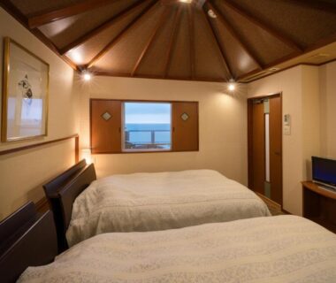 Twin beds, wooden vaulted ceiling, small sea view window, room at Yura Onsen Yaotome, Yamagata