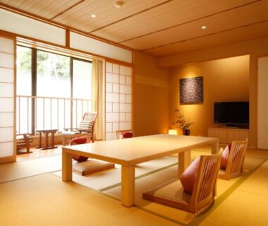 Tatami room with low table, floor chairs, shoji screens and balcony seating at Yuraku Kinosaki Spa & Gardens