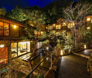 Nighttime courtyard with wooden balconies, stone path and water channel at Yuraku Kinosaki in Hyōgo