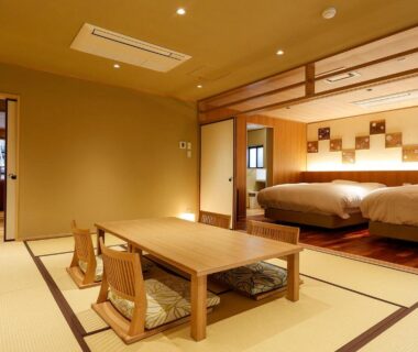 Tatami room with low table, zaisu chairs and raised twin beds at Yuraku Kinosaki Spa in Hyōgo