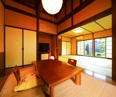 Traditional tatami room with low wooden table, zabuton cushions and shoji screens overlooking a garden at Yurari Rokumyo, Ōita