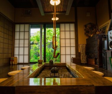 Sunken wooden hearth table with stools, shoji screens opening to a verdant garden at Yurari Rokumyo, Oita, Kyushu