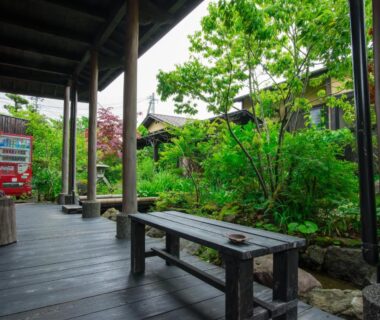 Covered wooden veranda with bench overlooking lush courtyard garden at Yurari Rokumyo in Ōita
