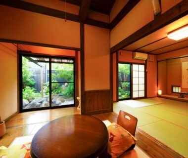 Tatami room with low round table, shoji screens and garden view at Yurari Rokumyo in Ōita, Kyūshū, Japan