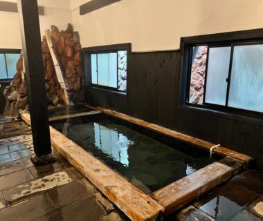 Indoor wooden-framed bath with stone floor and low windows at Yusai Bekkan, Kumamoto, Kyushu