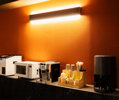 Counter with microwave, toaster, coffee machine and cups against warm orange wall at Yusai Bekkan in Kumamoto