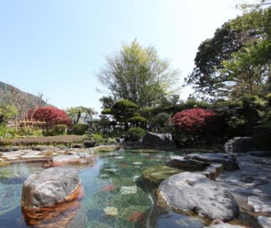 Outdoor stone onsen bath with garden and trees at Yusakaso in Kanagawa, Japan
