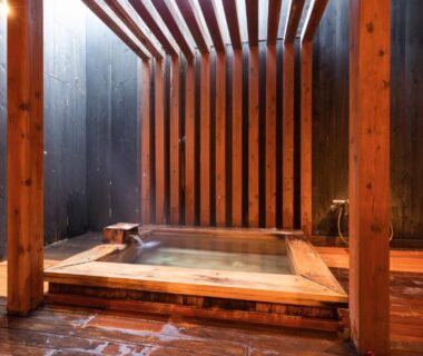 Indoor wooden onsen soaking tub with slatted privacy screens at Yushintei, Kanagawa ryokan
