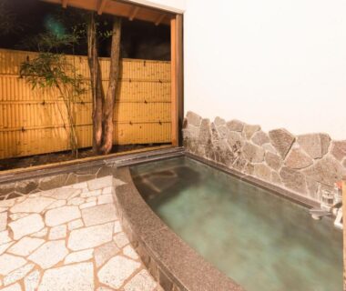 Stone bathing tub with bamboo screen and shower area at Yushintei in Kanagawa, Japan