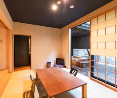 Tatami room with low wooden table, shoji screens and adjacent wooden bath area at Yushintei in Kanagawa