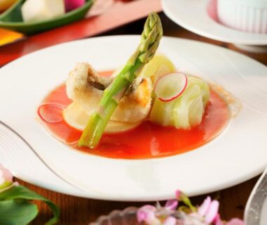 Asparagus and thinly sliced radish over a red sauce with garnish on a porcelain plate at Yutorelo Beppu