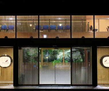 Glass entrance with wooden slatted facade and illuminated upper-level seating at Yutorelo Nasushiobara, Tochigi