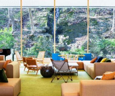 Bright lounge with sofas, armchairs and large windows overlooking wooded hillside at Yutorelo Nasushiobara Tochigi