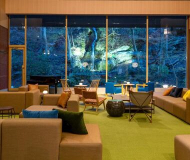 Modern ryokan lounge with large window overlooking wooded hillside at Yutorelo Nasushiobara in Tochigi
