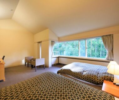 Twin beds, seating area and large window with forest view at Yutorelo Tateshina Nagano
