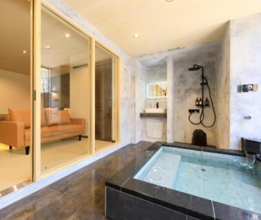 Glass-partitioned indoor stone bath with shower adjoining a guest room and seating at Yutorelo Tateshina, Nagano