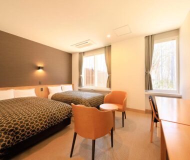 Bright twin room with two beds, seating area and desk at Yutorelo Tateshina Hotel in Nagano