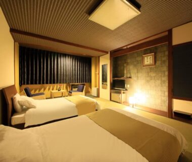 Twin beds on tatami with seating bay and warm lighting at Yutorelo Toyako, Hokkaidō, Japan
