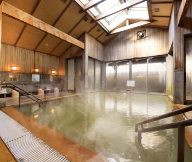 Communal indoor onsen with wooden beams and skylight at Yutorelo Toyako, Hokkaidō