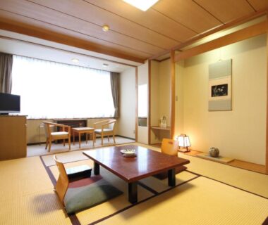 Tatami room with low table, zabuton cushions, alcove art and seating area at Yutorelo Toyako, Hokkaidō
