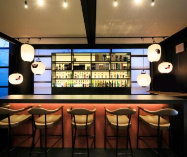 Bar counter with stools, backlit liquor shelves and paper lanterns at Yutorelo Yamaga in Kumamoto