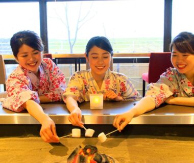 Three guests in yukata roasting marshmallows over an indoor hearth at Yutorelo Yamaga, Kumamoto, Kyushu, Japan