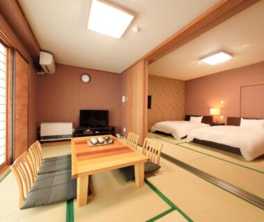 Tatami room with low table, chairs, two beds, shoji screens and TV at Yutorelo-an ANNEX Kanagawa