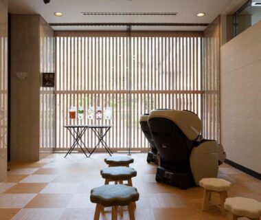 Massage chair and low stools by wooden slatted screen in ryokan lounge, Yutoriro Bandai Atami, Fukushima
