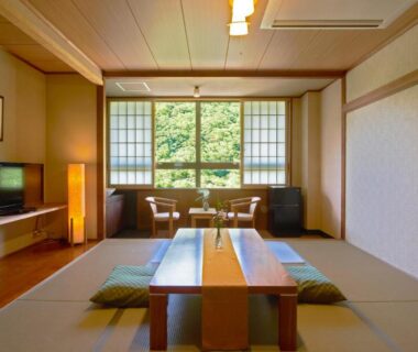 Traditional tatami room with low table, zabuton cushions and shoji screens framed by green view at Yutoriro Bandai Atami Fukushima