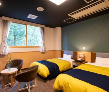 Bright twin bedroom with seating area and window view at Yutoriro Bandai Atami, Fukushima Tōhoku