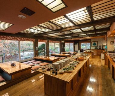 Spacious wooden dining hall with low table seating, buffet counters and garden views at Yuyado DAIICHI Hokkaidō