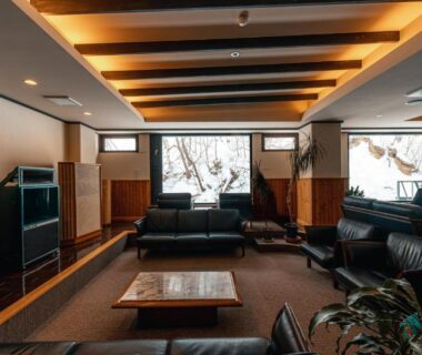 Interior lounge with leather sofas, low table and large window showing snow outside at Yuyado DAIICHI Hokkaidō