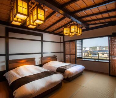 Traditional tatami room with twin futons, wooden beams, paper lanterns and city view in Ishikawa prefecture