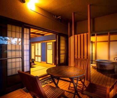Evening-lit tatami room with shoji screens, low table, chairs and a wooden soaking tub on the veranda Yuyaruru Saisai Ishikawa