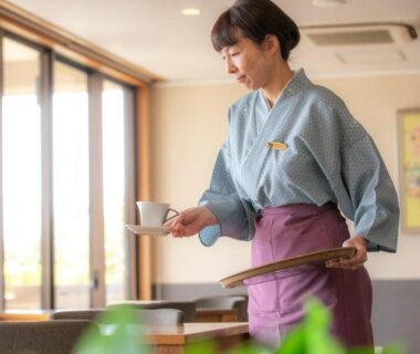 Woman in yukata-style uniform serving tea in dining room at Yuyaruru Saisai in Ishikawa, Chūbu
