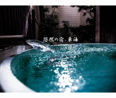 Circular wooden onsen tub with flowing water and foliage at a ryokan in Saga, Kyushu