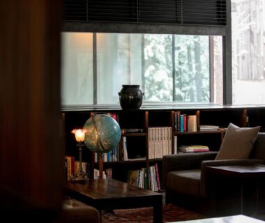 Cozy ryokan lounge with bookshelves, armchairs, globe and large window overlooking trees at Zaborin, Hokkaidō