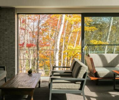 Sunlit lounge seating with low table and large windows revealing autumn white-barked trees at Zaborin Hokkaidō Japan
