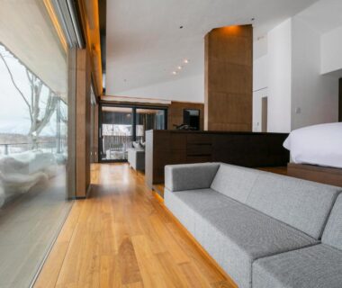 Spacious room with low bed, sofa and floor-to-ceiling windows showing snow, Zaborin Hokkaido