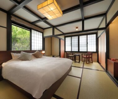 Spacious tatami room with Western bed, shoji screens and low table at Zao Onsen Omiya Ryokan, Yamagata
