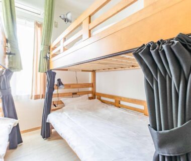 Dormitory with wooden bunk beds, individual privacy curtains and bright natural light