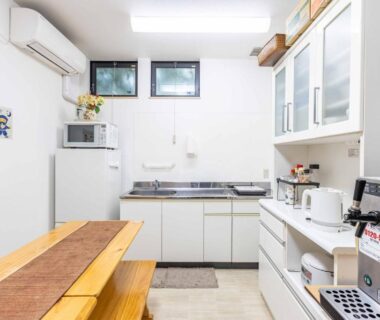 Shared kitchen with wooden bench, appliances and sink at add-Hostel Uji Cha-gan-ju-tei Kyoto Kansai