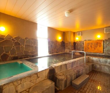 Stone onsen baths with wooden ceiling and warm lighting at caffel Hina-no-sato Ōita