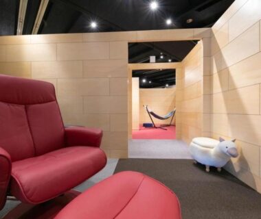 Red armchair and ottoman in wood-paneled corridor at caffel Hina-no-sato, Ōita, Kyūshū