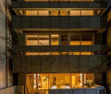 Night exterior of multi-story ryokan with warm-lit windows and street entrance in Asakusa, Tokyo