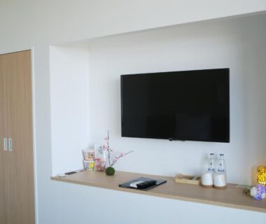 Recessed TV alcove with shelf holding water bottles and simple decorative plant at gran terrace Le Lien Hakone, Kanagawa