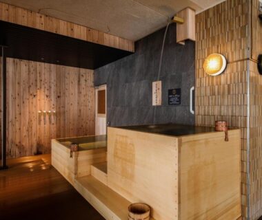 Indoor wooden onsen baths with stone walls and warm lighting at jyozankei SHIKAnoYU Hokkaidō