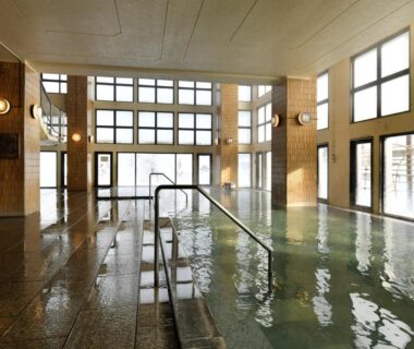 Spacious tiled indoor onsen with large windows and handrail at jyozankei SHIKAnoYU Hokkaidō