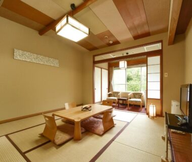 Tatami room with low table, floor chairs, shoji doors and greenery outside at jyozankei SHIKAnoYU Hokkaidō